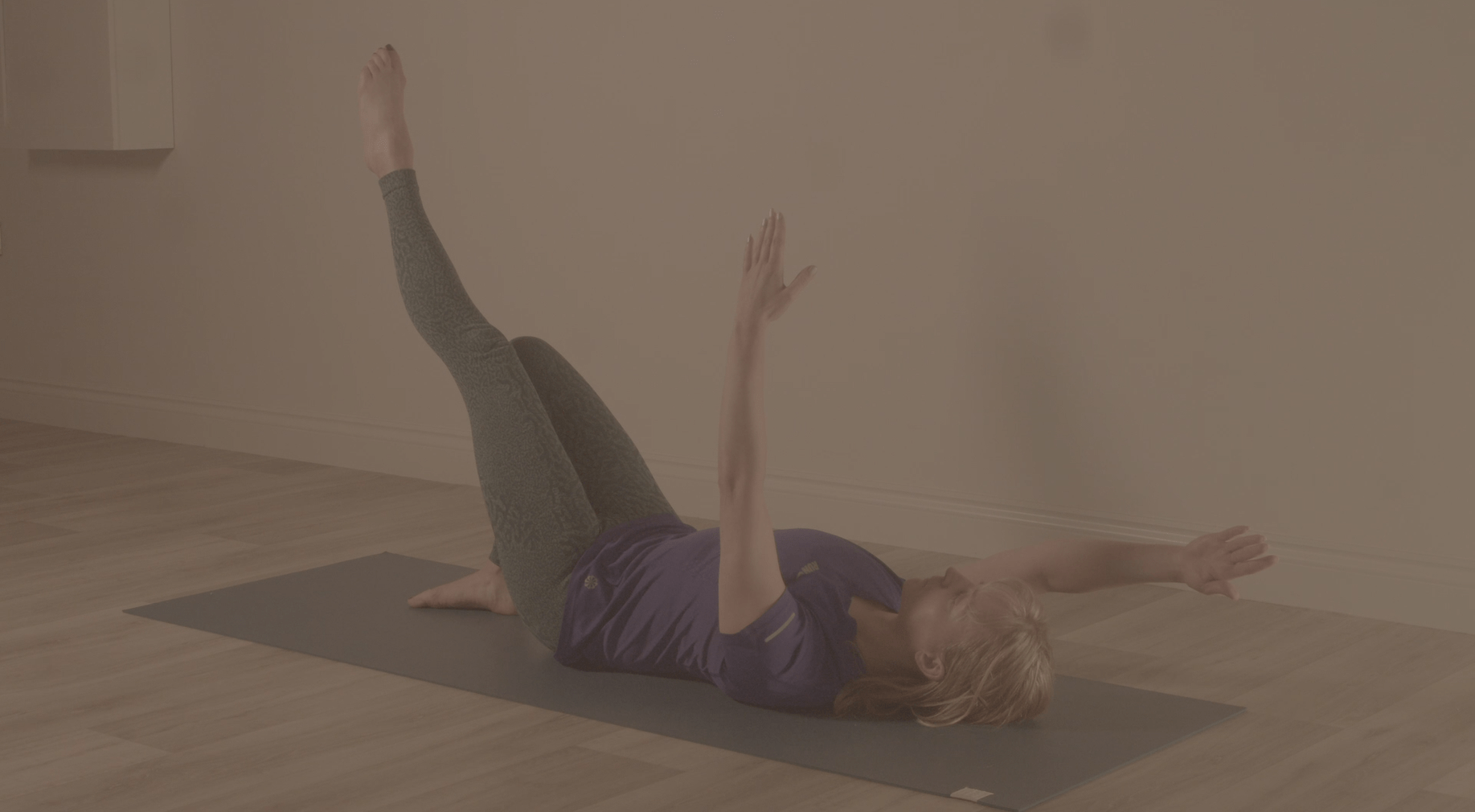 Instructor performing a hernia rehabilitation exercise, laying on a yoga mat on the floor.
